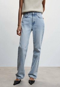 Jeans rectos de color azul claro con una cintura alta, textura ligeramente desgastada y diseño clásico de cinco bolsillos. Combinados con una blusa de punto beige.