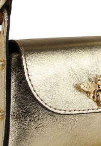 Metallisch goldene Handtasche mit Klappenverschluss, ausgestattet mit einem Bienendetail und goldenen Beschlägen. Glatte Textur mit sichtbaren Nahtakzenten.