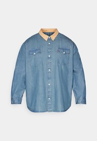 Camicia di jeans a maniche lunghe blu chiaro con colletto beige a contrasto, bottoni bianchi sulla parte anteriore e due tasche sul petto con bottone.