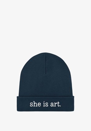 Bonnet en maille bleu marine avec bord replié, arborant le texte brodé blanc « elle est art. » centré à l'avant.