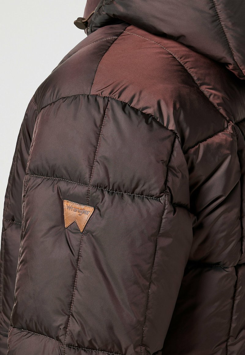 Giacca a vento marrone con design trapuntato, texture lucida e patch in pelle con logo. Presenta tessuti di diverse tonalità di marrone.