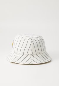 Bucket hat lavet af hvidt bomuld med sorte vertikale striber. Har en blød skygge og et lille logo-patch. Struktureret stof med synlige syninger.