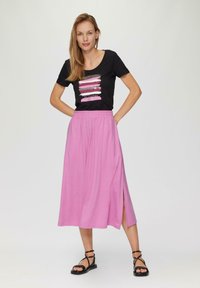 Black cotton t-shirt with a colorful striped graphic design, paired with a light pink, knee-length skirt featuring a side slit and elastic waistband.