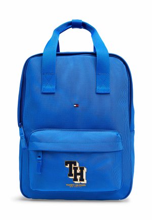 Sac à dos bleu Tommy Hilfiger avec poche avant zippée, doubles poignées, petit logo près du centre supérieur, et grand "TH" brodé sur la poche avant.