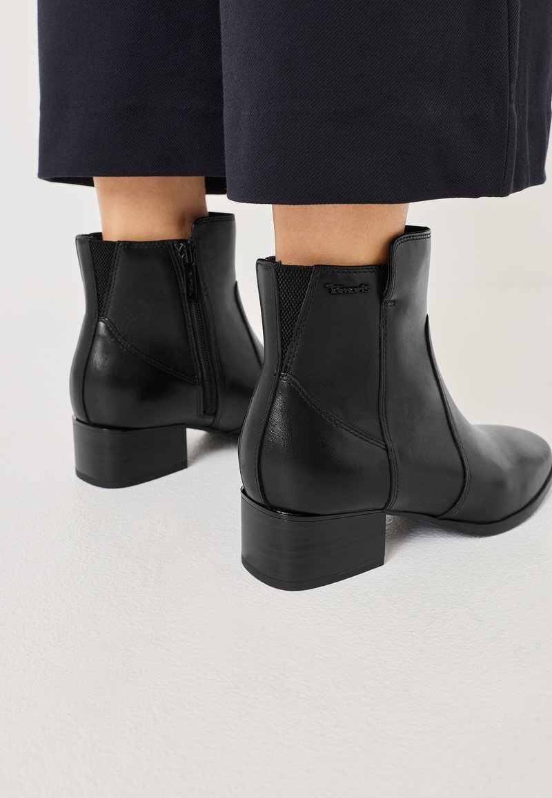 Schwarze Leder-Stiefeletten mit runder Zehenform, seitlichem Reißverschluss und Blockabsatz. Verfügt über elastische Einsätze für Flexibilität und eine glatte Textur.