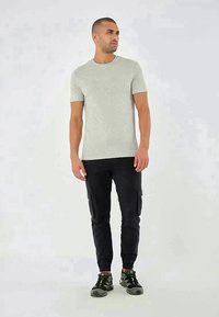 Light grey short-sleeve t-shirt paired with black cargo pants and black athletic shoes, featuring a slim fit and simple design.