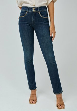 Jeans de cintura alta de color azul oscuro con dos bolsillos frontales, costuras en contraste y botones de hardware dorados. Corte ajustado hasta el tobillo con un ligero deshilachado.