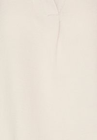 Ljusbeige blus med en mjuk textur, med V-ringning, subtila plisséer och en slät finish.