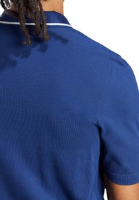 Polo blu navy in tessuto strutturato con strisce bianche a contrasto sul colletto, maniche corte e vestibilità comoda.