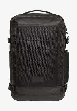 Mochila negra con una superficie texturizada, acentos suaves, bolsillo lateral y correas. Presenta una forma rectangular y un logotipo rectangular en la parte inferior.