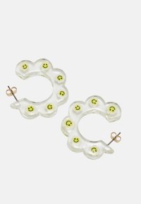 Brincos de argola em acrílico transparente com detalhes em amarelo de rosto sorridente, apresentando uma forma floral e um fecho de pino em tom dourado.