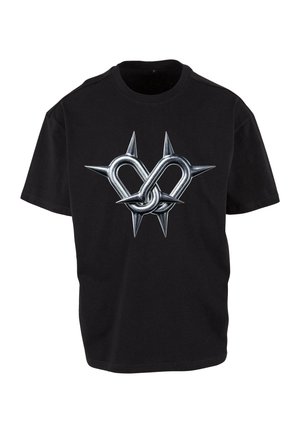 Melnā T-kreklu izstrādājums ar metāla sirds dizainu, kas iesaistīts adatās, uzsverot asu un neparastu estētiku sudrabā un melnā krāsā.