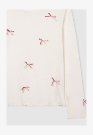 Top a maniche lunghe di colore crema con piccoli fiocchi di raso rosa sparsi e orlo arricciato sulle maniche e sul fondo.