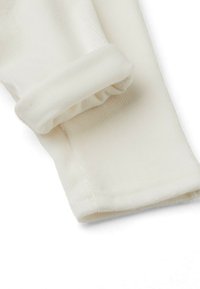 Biały materiał sztruksowy z wywiniętym mankietem, charakteryzujący się subtelną, prążkowaną fakturą i starannym przeszyciem wzdłuż brzegu.