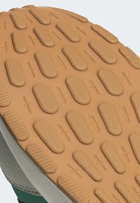 Gummisula med ett strukturerat mönster som innehåller ovala och rektangulära spår. Brun färg med beige bas, designad för grepp och stabilitet.