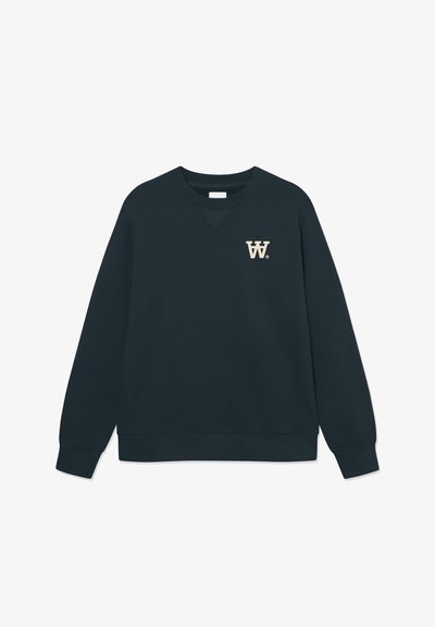 Sweatshirt bleu marine foncé en tissu doux, avec un col rond, des manches longues et un petit logo "W." beige sur la poitrine gauche.