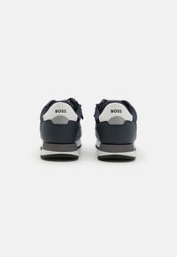 Marineblå og grå sneakers med en glatt skinnfinish. Har en hvit hælflik med "BOSS"-logo og en hvit og grå stripet såle.