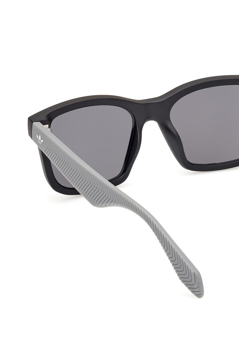 Black sunglasses with gray textured temple arms, featuring dark lenses and a geometric frame design.