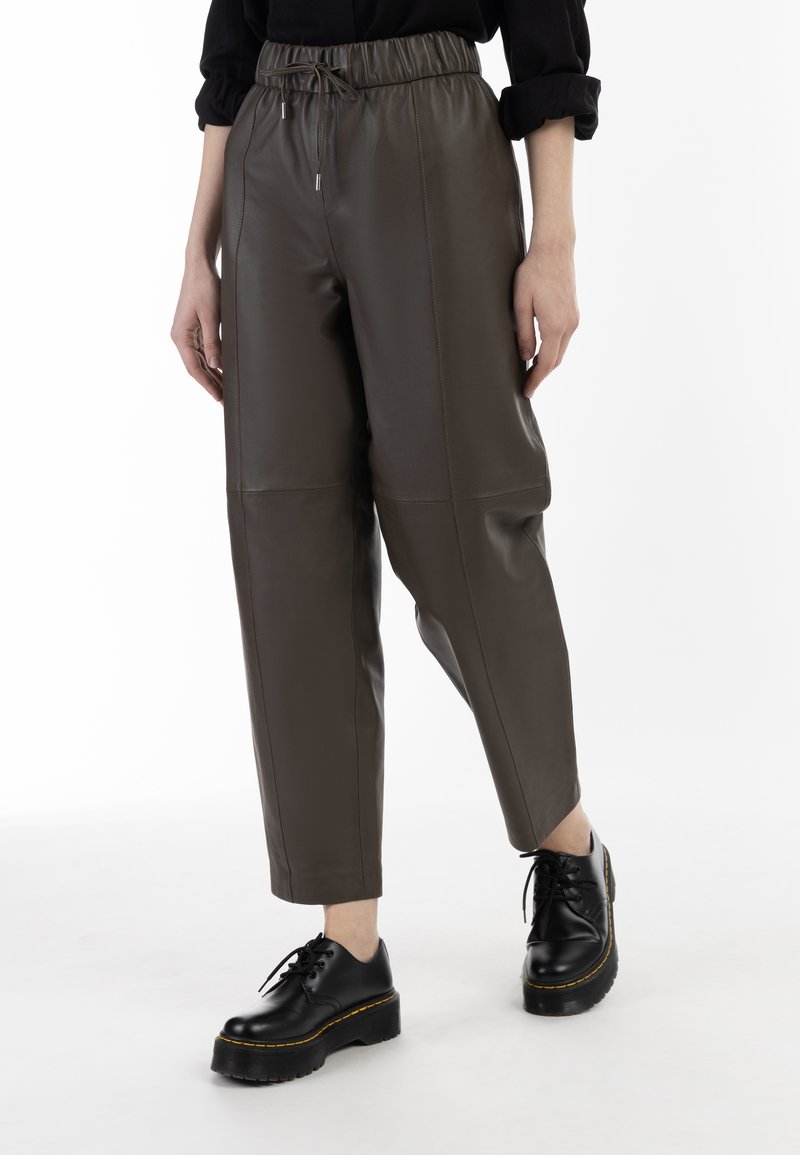 Brune faux læder tapered bukser med elastisk talje og sidesømme, parret med sorte snørebånds platform sko.