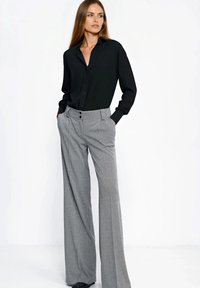 Czarna koszula na guziki z długimi rękawami, zestawiona z szerokimi spodniami o wzorze pepitki w szarym kolorze, wyposażonymi w dwa przednie guziki i boczne kieszenie.