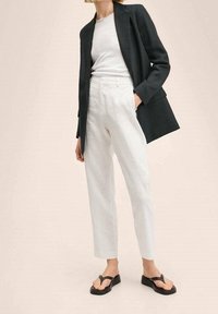 Černé sako, bílé tričko a bílé lněné kalhoty. Obuv tvoří černé žabky s plochou podrážkou. Jednoduchý, přizpůsobený design.