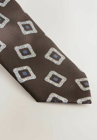 Brown tie featuring a textured pattern of white and blue squares outlined in silver. The fabric has a subtle ribbed texture.