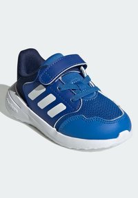 Niebieskie dziecięce trampki z białymi paskami, zapięcie na rzep i sznurówki, z białą podeszwą oraz przewiewnym obszarem palców z siatki.