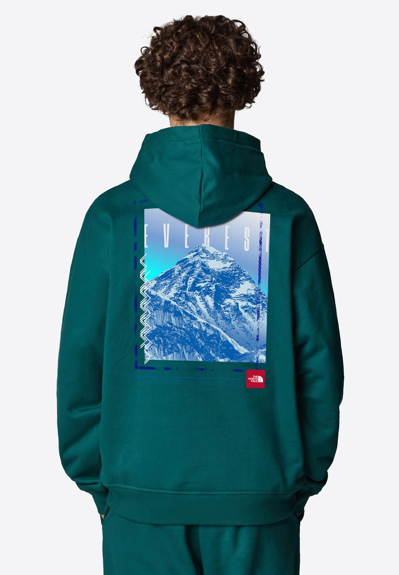 Sudadera en color azul verdoso con capucha, que presenta un gráfico del Monte Everest en la parte posterior, texto en negrita y un pequeño logotipo rojo en el lado inferior.