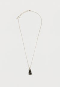 Ασημένιο κολιέ αλυσίδας με ένα μικρό μαύρο μενταγιόν σε σχήμα ζελέ αρκούδας σε απλό λευκό φόντο.