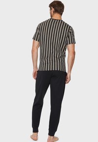 Kortærmet stribet sort og hvid pyjamashirt med gule accenter, kombineret med ensfarvede sorte pyjamabukser. Blødt stof, afslappet pasform.