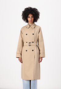 Beżowy trench coat z podwójnym zapięciem na guziki, paskiem w talii, szerokimi klapami i długimi rękawami; gładka tekstura i dopasowany krój.