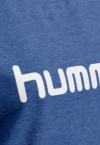 T-shirt in cotone blu con lettere bianche in grassetto che scrivono "humm" sul petto, realizzato con un tessuto morbido e leggermente strutturato.