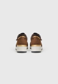 Brown suede sneakers with a white rubber sole, gold accents at the heel, and a lace-up design. Rear view shows detailed stitching and a textured finish.