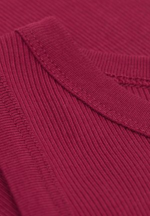 Prążkowana, bordowa dzianina z okrągłym dekoltem, z teksturowanymi wzorami i widocznymi detalami szwów. Zbliżenie podkreśla teksturę.