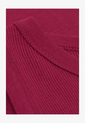 Ribbad vinröd stickad tyg med rundad halsringning, som har texturerade mönster och synliga sömdetaljer. Närbild visar texturen.