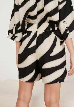 Schwarze und cremefarbene Shorts mit einem auffälligen Zebramuster, ausgestattet mit einem elastischen Bund und einer lässigen Passform, aus leichtem Material.