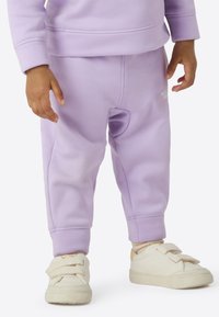 Vaaleanvioletit taaperoiden collegehousut, joissa on joustavat lahkeensuut ja pehmeä materiaali. Yhdistetty valkoisiin kenkiin, joissa on kaksi tarranauhaa.