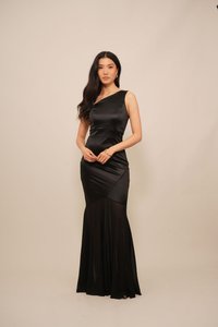 Musta satiini iltapuku, jossa on tiukka bodice, yhdelle olalle suunniteltu malli ja liehuva hame. Ominaisuuksia ovat sileä pinta ja hienovaraiset laskosten yksityiskohdat.