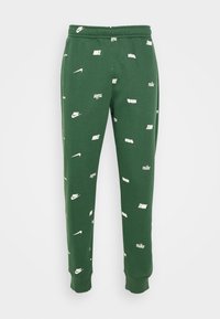 Gröna träningsoverallsbyxor i en bomullsblandning, med ett spritt vitt Nike-logo och textmönster, med elastisk midja och muddar.