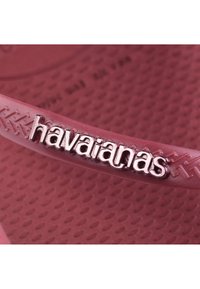 Șlapi Havaianas în burgundy, cu o curea netedă și un logo embossat. Talpa texturată oferă aderență și confort.