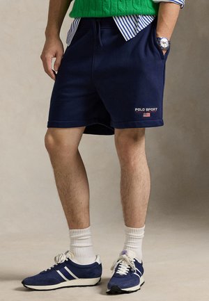 Granatowe bawełniane spodenki z bocznymi kieszeniami, elastycznym pasem i logo "POLO SPORT". Połączone z granatowymi tenisówkami i białymi skarpetkami do kostki.