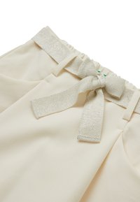 Pantaloni color crema con vita elasticizzata, dotati di una cintura in nastro argento texturizzato annodata a fiocco davanti e tasche laterali.