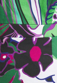 Tissu floral coloré présentant de grandes fleurs vertes, violettes et noires avec des accents vibrants, sur un fond doux et texturé.