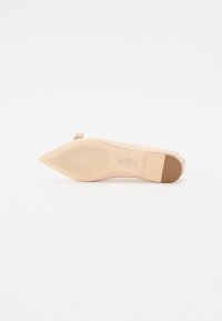 Chaussure plate rose avec un bout pointu, arborant un motif matelassé sur un matériau doux. La semelle est texturée avec un petit talon et des accents en caoutchouc.