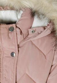 Veste matelassée rose clair avec bordures en fausse fourrure, boutons-pression et texture matelassée. Dispose d'un col montant et d'une doublure intérieure douce.