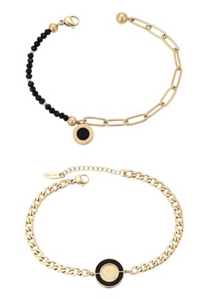 Két arany lánc karkötő: az egyik fekete gyöngyökkel és kerek fekete-arany medállal, a másik láncszemes lánc és kerek fekete-arany medál középen.