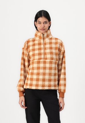 Pull en polaire à carreaux marron et crème avec un col haut et un design à demi-zip. Présente des poignets côtelés et une apparence texturée et confortable.