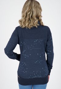 Sudadera azul marino con estampado de pájaros, con cuello alto y mangas largas. Tejido texturizado con un dobladillo ligeramente curvado en la parte trasera.