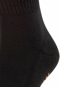 Calcetín negro con un puño acanalado, textura suave y talón reforzado. Presenta un pequeño logo naranja cerca del dedo del pie.