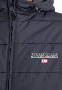 Granatowa kurtka puchowa z zamkiem błyskawicznym. Posiada kaptur, przeszywane panele oraz odblaskowe logo z akcentem norweskiej flagi.